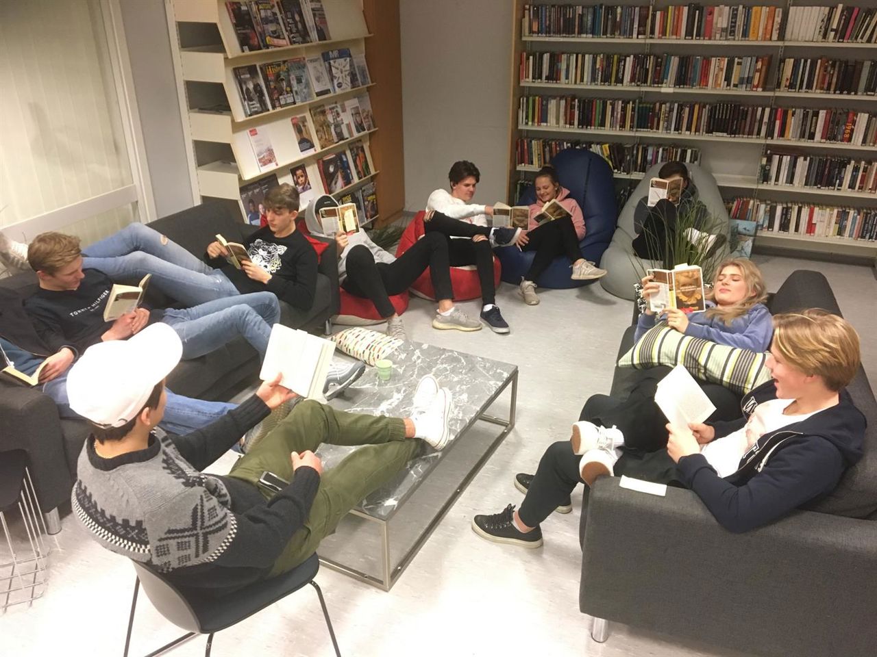 Bilde av elevar som les bøker på biblioteket